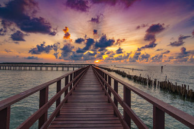 Pier over sea against sky during sunset