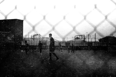 Person standing on chainlink fence in field