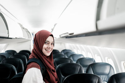 Portrait of smiling young woman standing in airplane