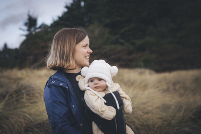 A woman with an infant is standing on the californian beach