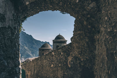 View of tower against sky seen through arch wall in ravello, italy