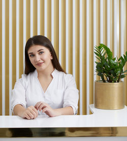 Portrait of young woman sitting on table