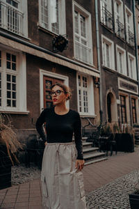Portrait of young woman standing against building in gdansk - old town