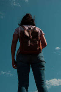 Rear view of man standing against blue sky