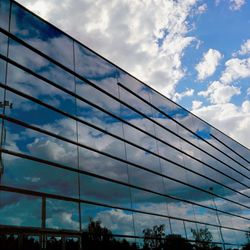 Low angle view of modern building against cloudy sky