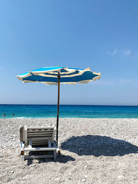 Deck chairs on beach against blue sky