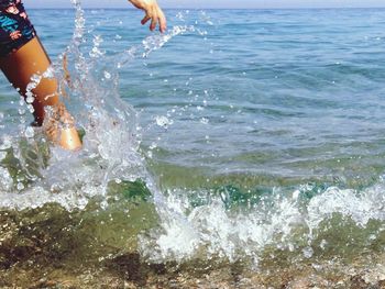 Low section of man surfing in sea