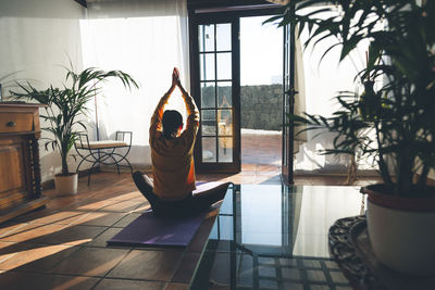 Young caucasian brunette woman practicing yoga at home sitting in lotus pose.