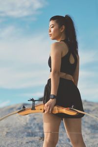 Portrait of young woman standing against sky during sunset