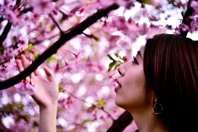 Close-up portrait of woman with pink flowers against blurred background