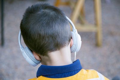 Rear view of boy listening music on headphones