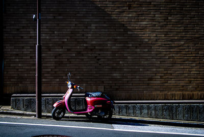 Man cycling on street against brick wall