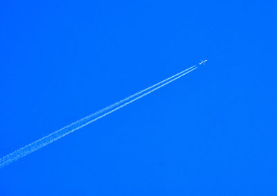 Low angle view of vapor trail against clear blue sky