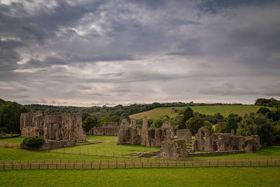 Old ruin on field against cloudy sky