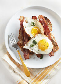 Two eggs sunny side up bacon and toast
