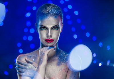 Portrait of naked woman with glitter against blue background