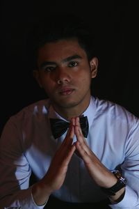 Portrait of young man against black background