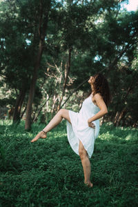 Young woman dancing while standing against trees in forest