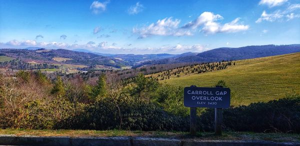 Road sign on landscape against sky