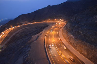 Road passing through illuminated highway at night