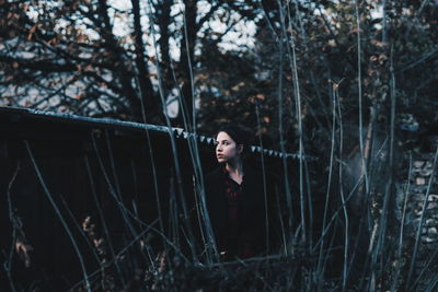 Young woman standing against trees in forest