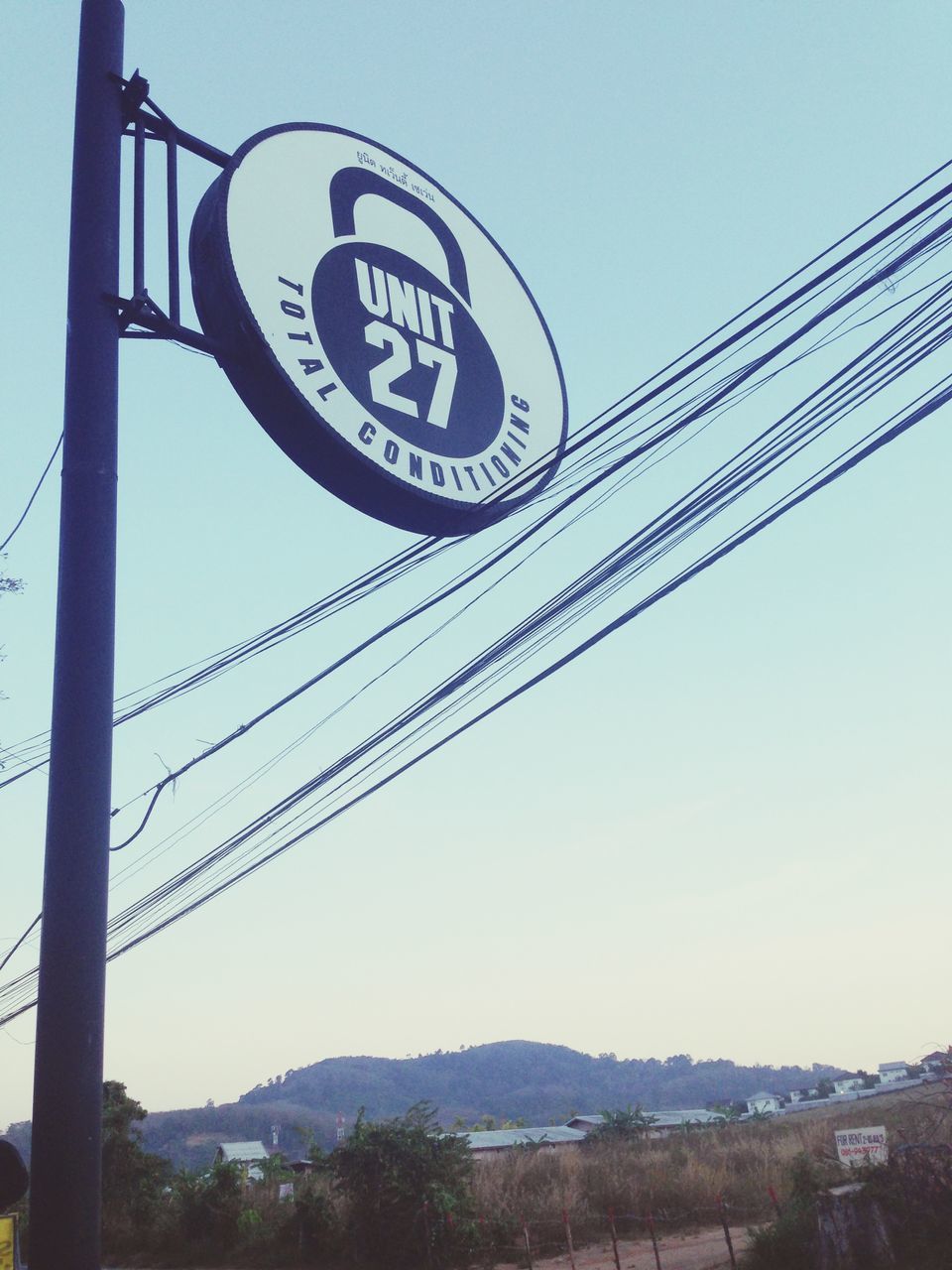 clear sky, power line, communication, electricity pylon, cable, text, connection, low angle view, electricity, power supply, mountain, sky, western script, technology, fuel and power generation, road sign, information sign, copy space, day, transportation