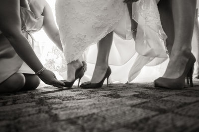 Woman helping bride to wear shoes