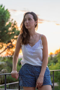 Young woman standing against trees