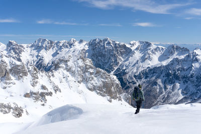 Man walking in the snow in front of the mountain range