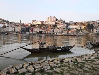 Sailboats moored on river by buildings in city against clear sky