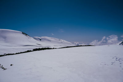 Scenic view of snow covered landscape against clear blue sky