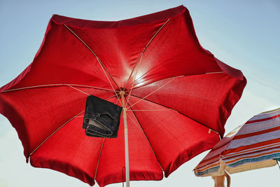 Low angle view of hot pants hanging on red parasol against clear sky