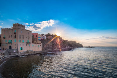 View of buildings at beach against sky during sunset