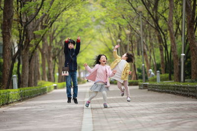 Full length of happy children on footpath at park