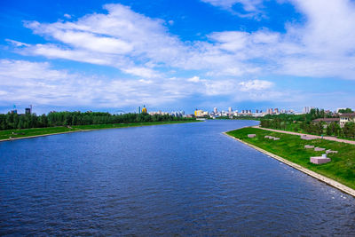 View of city at waterfront against cloudy sky