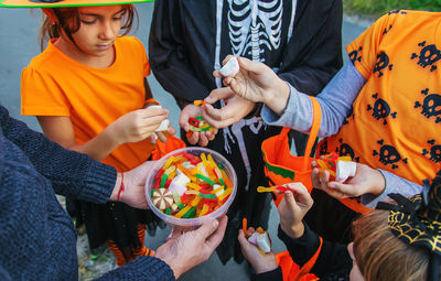 Midsection of man giving candies to kids