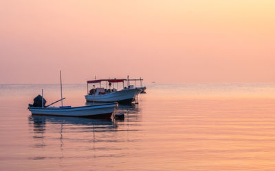 Fishing boat in sea against sky during sunrise