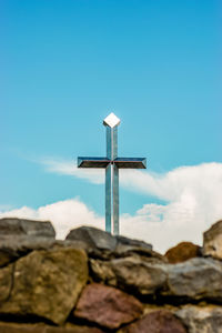 Low angle view of cross on rock against sky