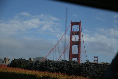 Low angle view of suspension bridge against cloudy sky