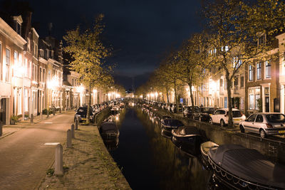 Boats moored on illuminated city at night