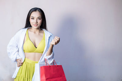 Portrait of young woman standing against wall