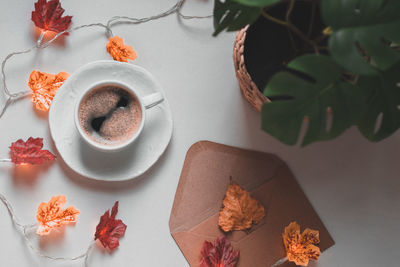 Mug of coffee with garland leaves on the bedside table.