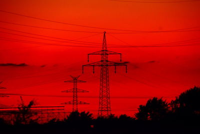 Low angle view of silhouette electricity pylon against romantic sky