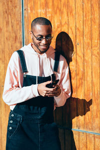 Portrait of young man standing against wooden wall