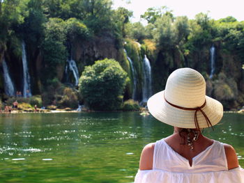 Rear view of woman wearing hat looking at waterfall