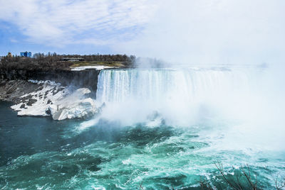 Scenic view of waterfall against sky