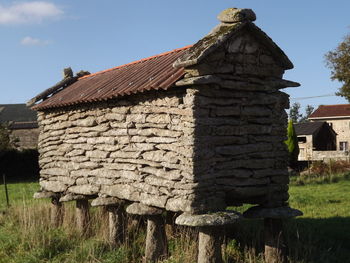 Old wooden house on field against sky