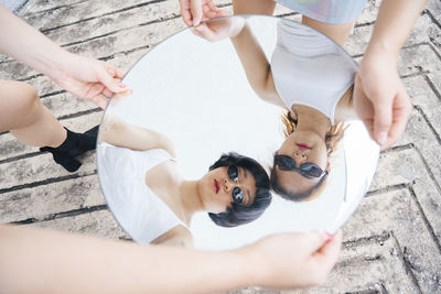 Reflection of lesbian sisters holding mirror outdoors