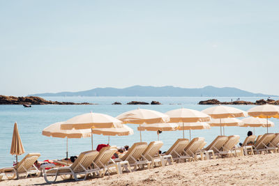 Chairs on beach by sea against sky