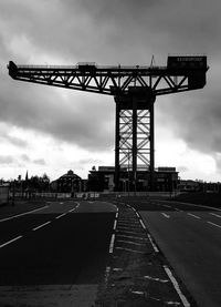 Road sign on bridge against sky in city